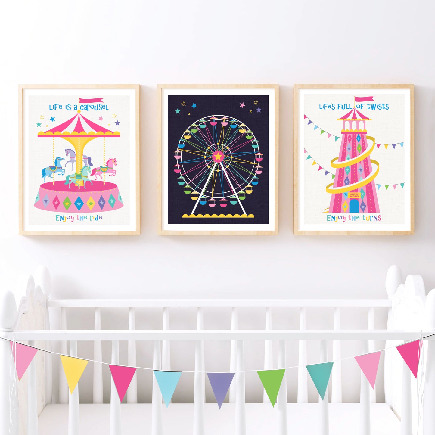 Three colorful framed prints above a crib with a bunting banner.