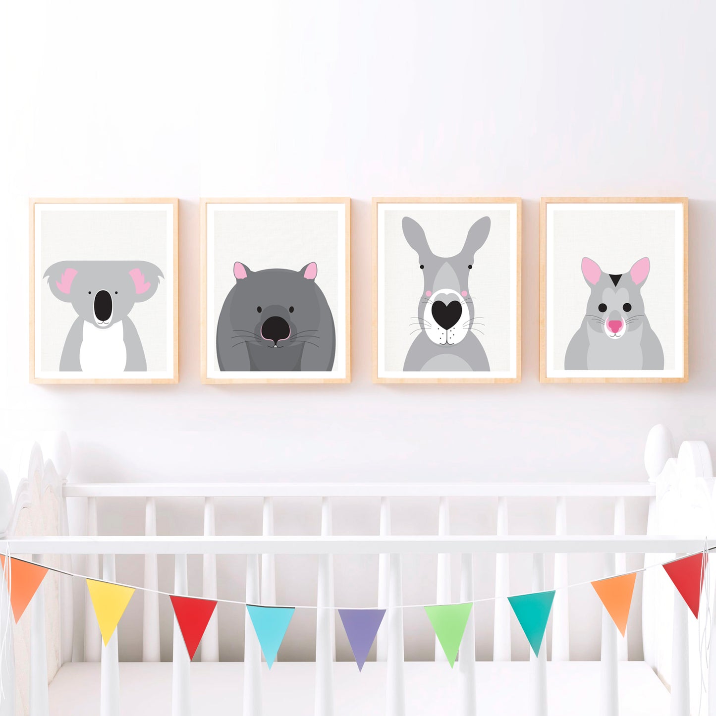 Prints are displayed above a crib. Each print features a different Australian animal:  koala, wombat, kangaroo, and possum. The illustrations are whimsical and gender neutral creating a playful nursery decor theme.