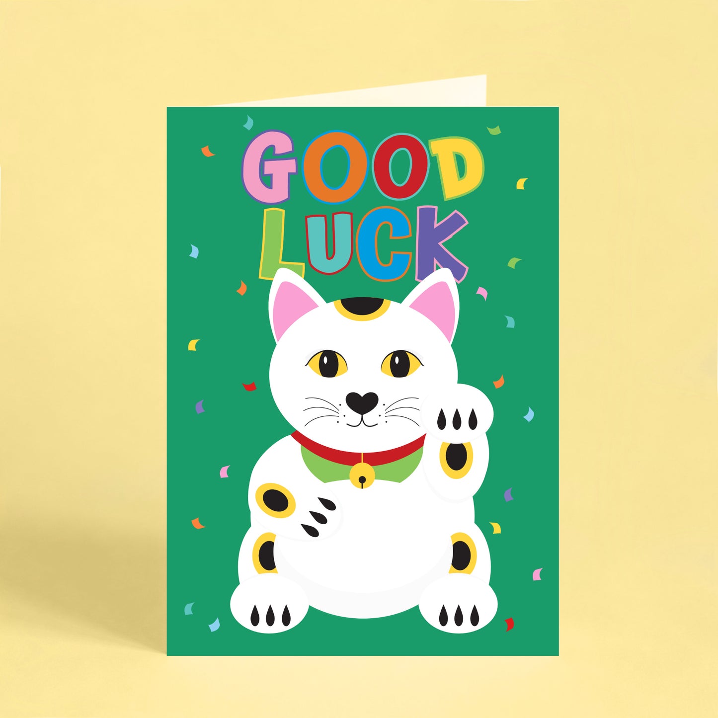 Colourful good luck greeting card featuring a white lucky cat (maneki neko) on a bright green background with rainbow lettering, confetti and the words "Good Luck". Perfect for new jobs, exams, graduations and new beginnings.
