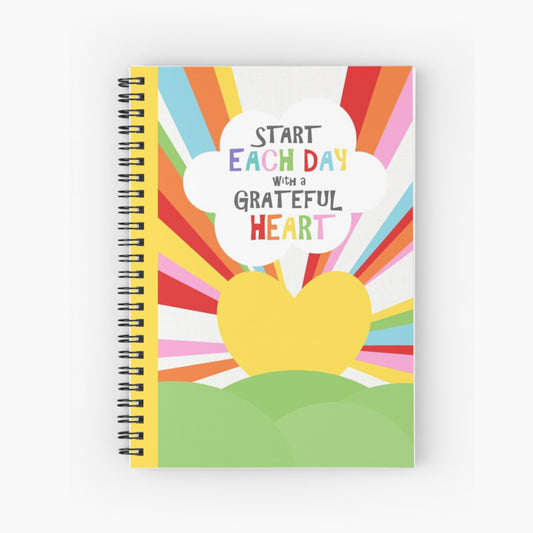 spiral notebook with inspiration quote on the cover and rainbow sunrise heart