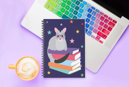 spiral notebook with possum illustration sitting on laptop