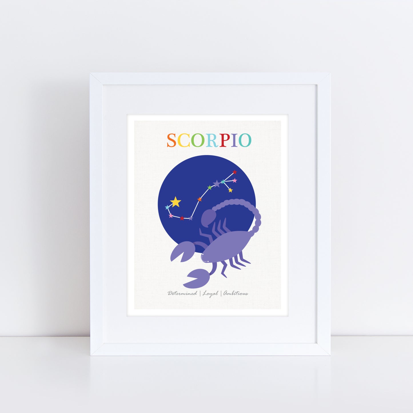 Framed Scorpio zodiac art print featuring a purple scorpion with a constellation illustration against a deep blue circular background. The word 'Scorpio' is written at the top in colorful letters, with the traits 'Determined | Loyal | Ambitious' listed below. The print is displayed in a white frame.