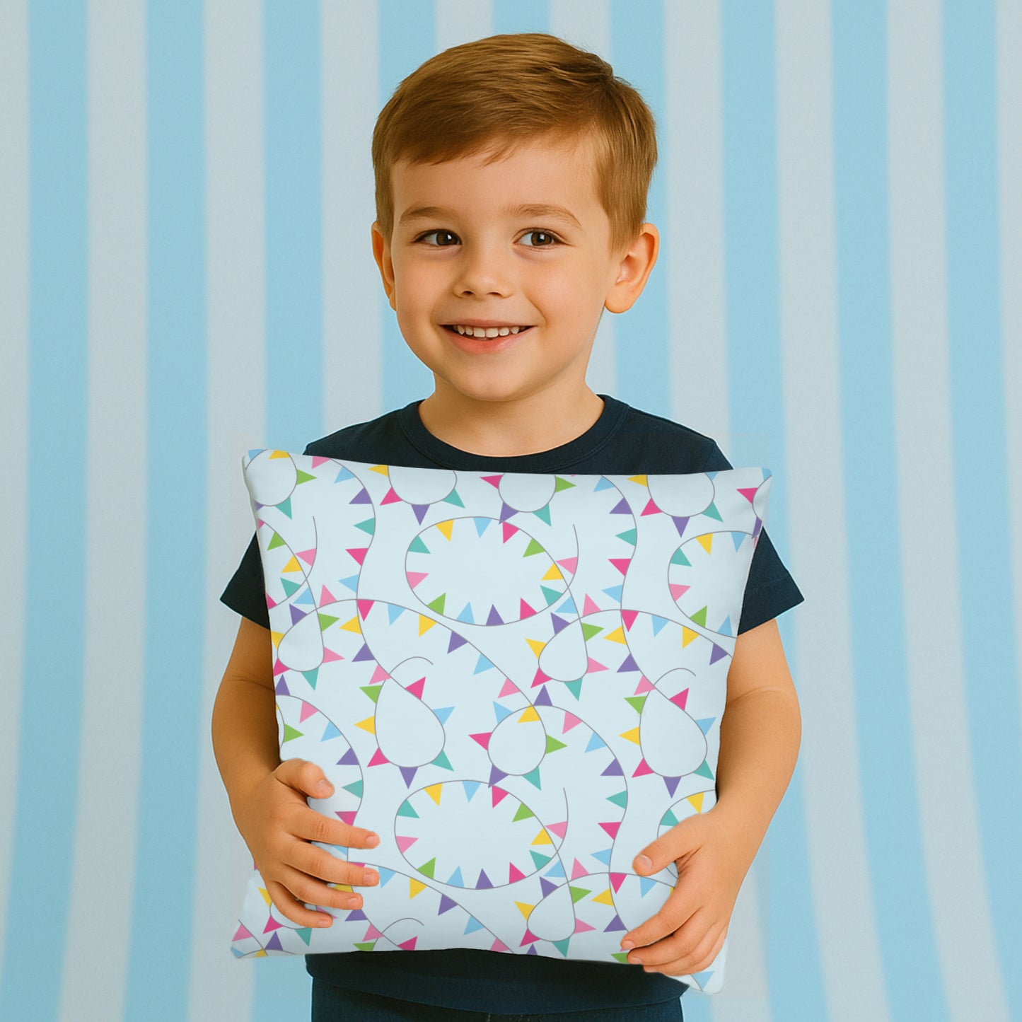 Child holding a pillow with colorful bunting pattern against a striped background