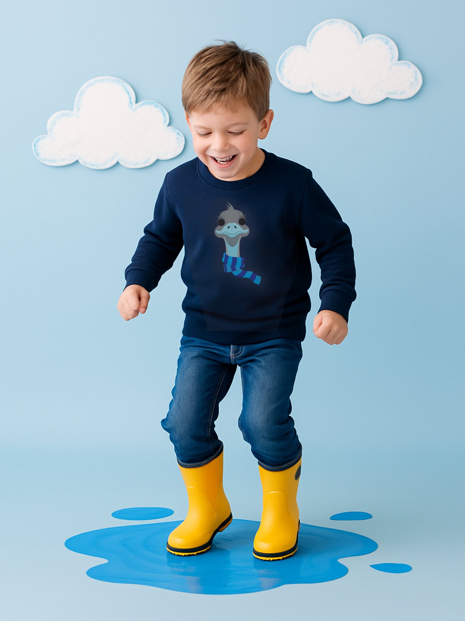 Boy in navy blue jumper with emu design jumping in puddles