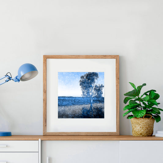 blue Australian landscape photograph of a single gum tree by the banks of a river in a frame in a study