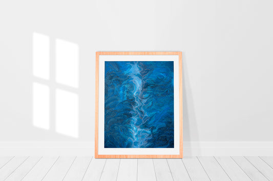 print in a frame of abstract painting in shades of blue is reminiscent of a breaking wave on the ocean seen from above