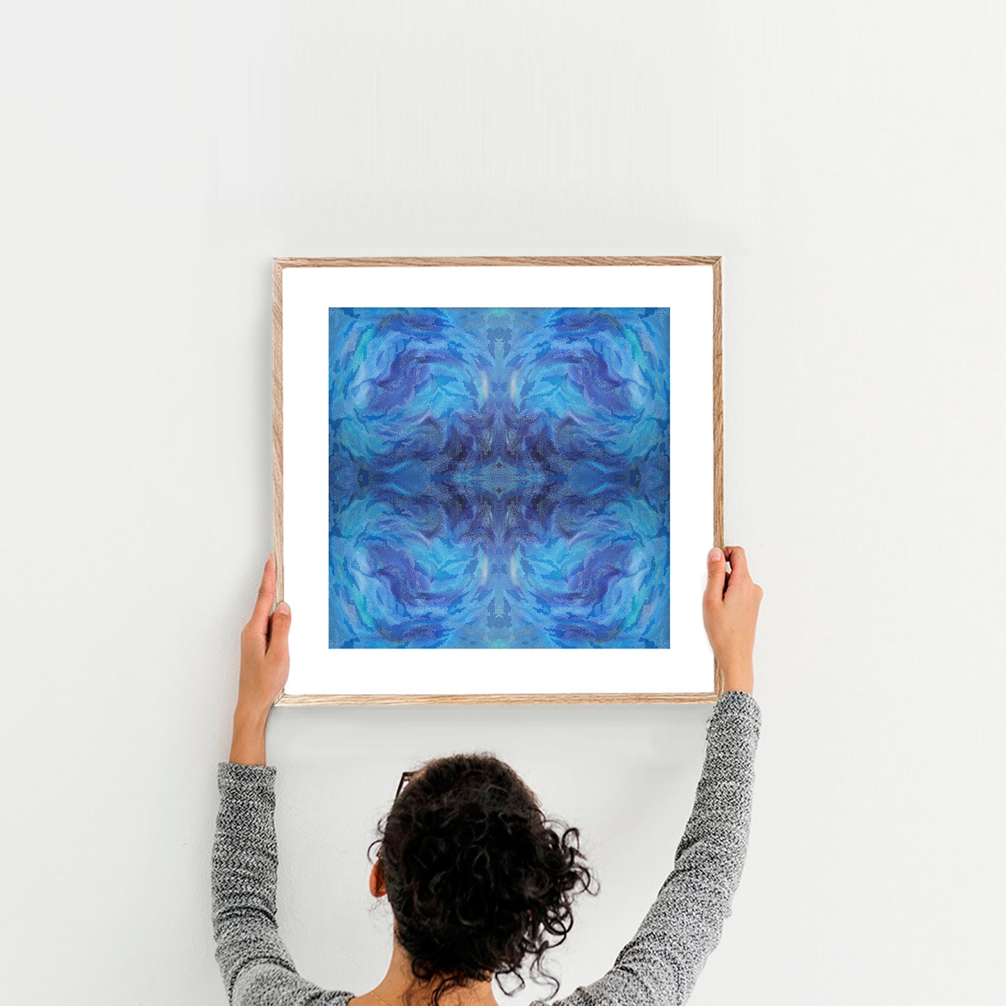 Person holding up an abstract blue mandala wall art celebrating summer and sea movement