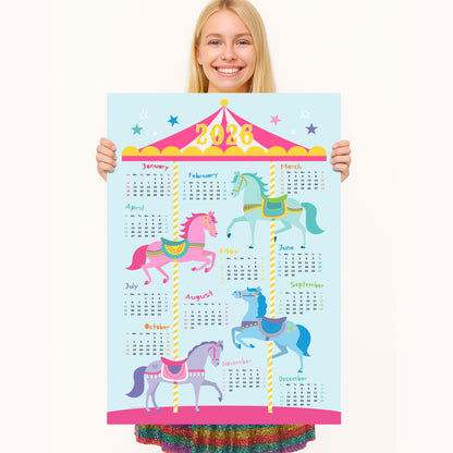 Person holding a colorful 2026 calendar with carousel horses design