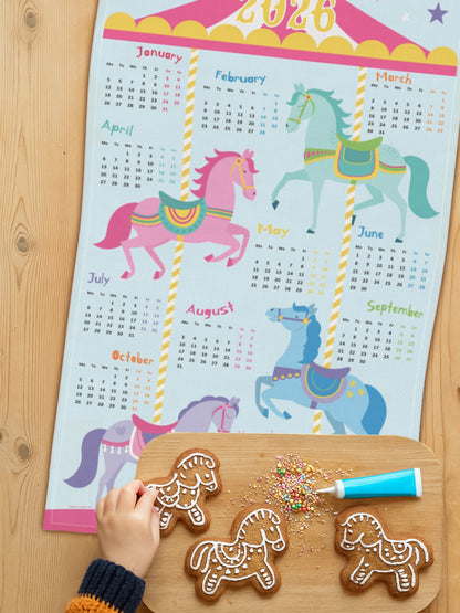 Tea towel with carousel horse design on kitchen table with horse cookies