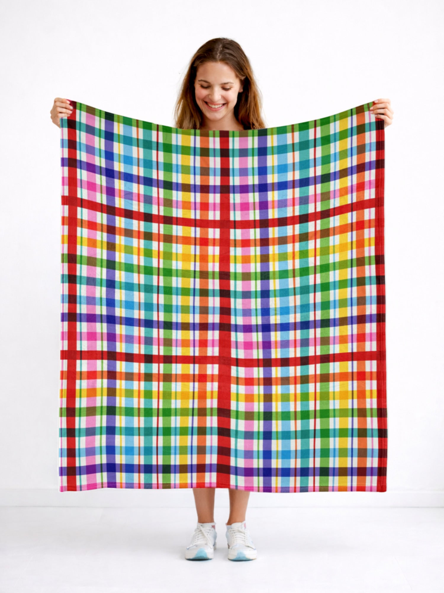 Person holding a colorful plaid blanket against a white background