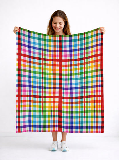 Person holding a colorful plaid blanket against a white background