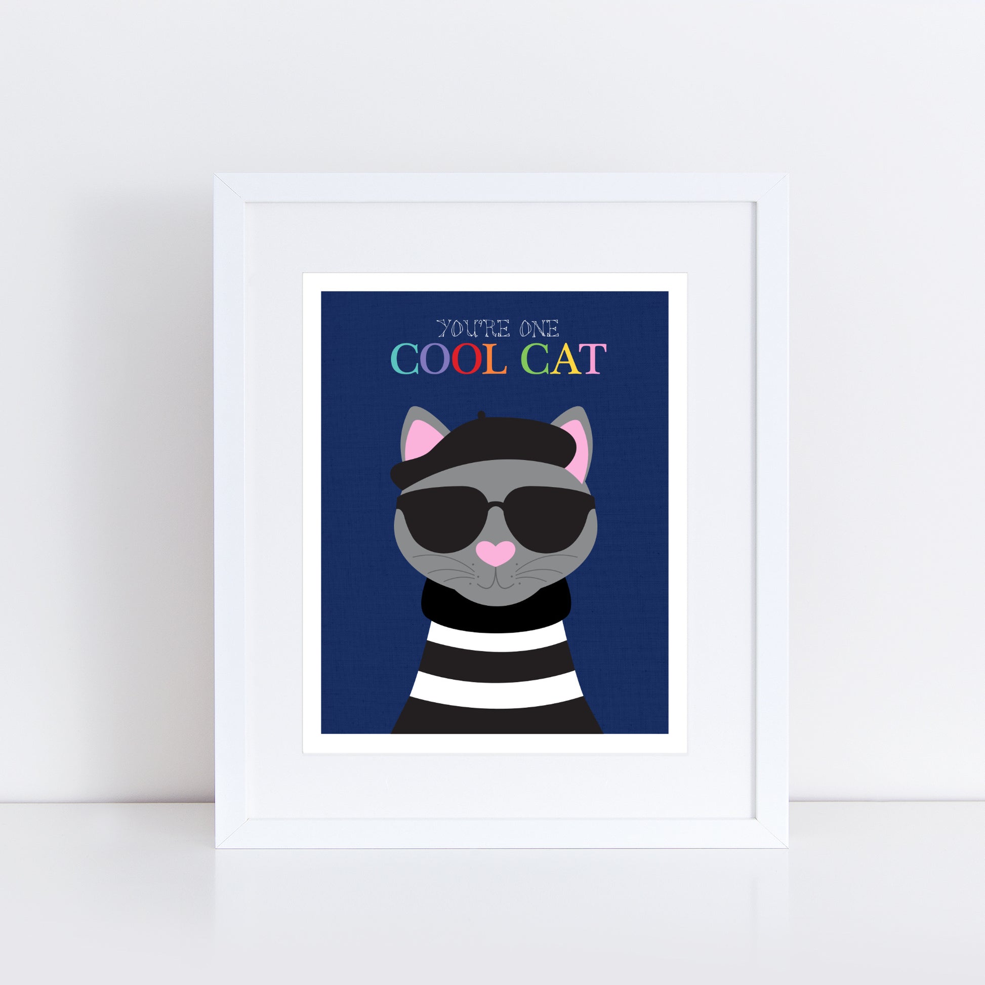 Art print featuring a grey cat wearing a black beret and dark sunglasses against a deep navy blue background. The cat has a pink heart-shaped nose and is dressed in a black and white striped jumper. Above the cat, the text reads "You're One Cool Cat" in a playful rainbow font.