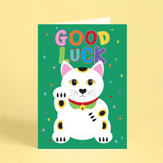 Colourful good luck greeting card featuring a white lucky cat (maneki neko) on a bright green background with rainbow lettering, confetti and the words "Good Luck". Perfect for new jobs, exams, graduations and new beginnings.