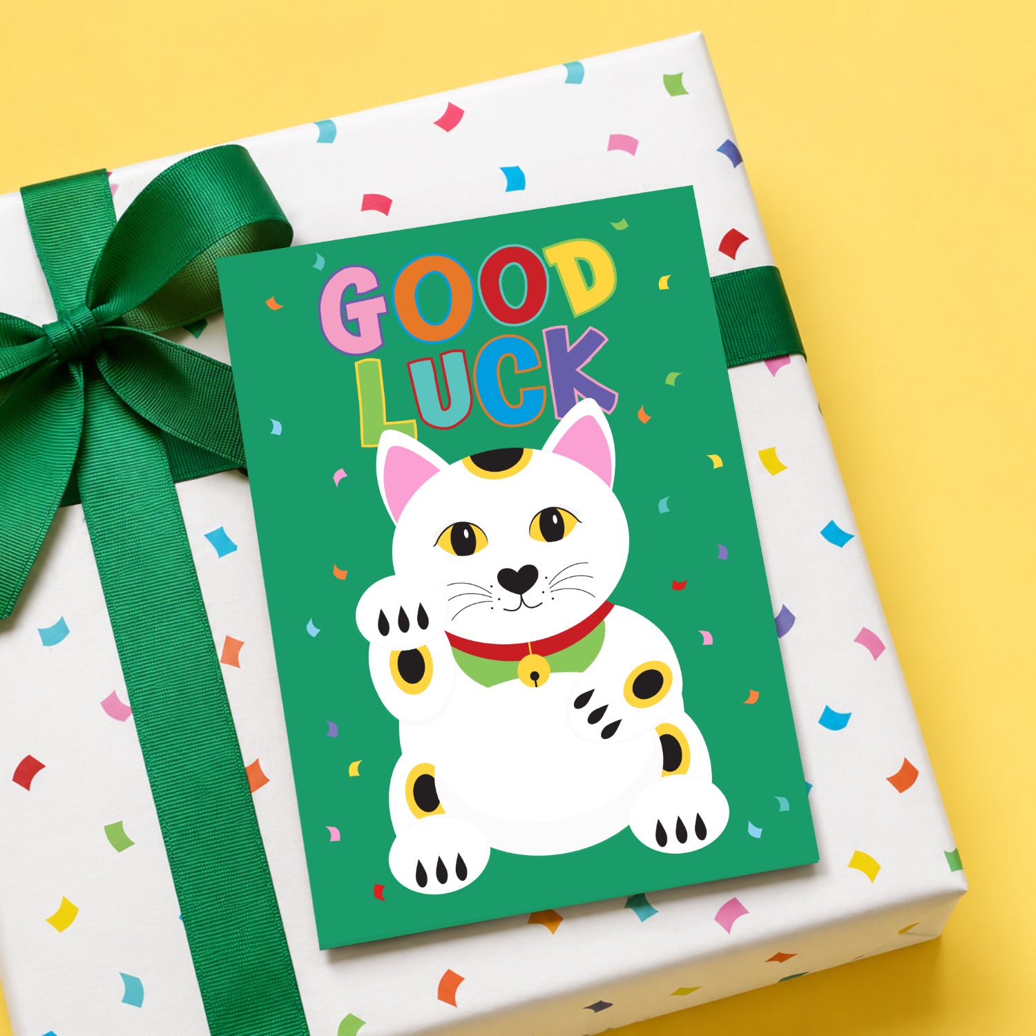 Gift box with a 'Good Luck' card featuring a cat illustration on a yellow background