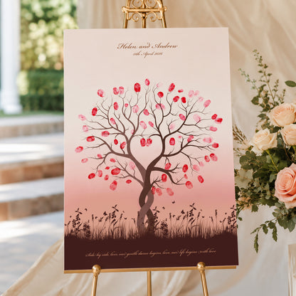 Elegant fingerprint tree wedding guest book sign displayed on a gold easel at a romantic outdoor wedding reception with soft golden sunset lighting and blush floral styling.