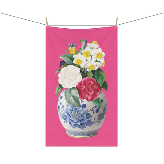 stunning tea towel, featuring a vibrant bouquet of camellias, pansies, and other delightful blooms set against a striking hot pink background.