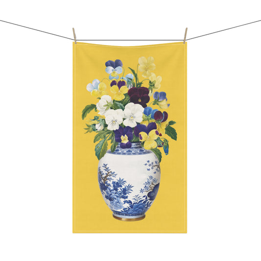 delightful tea towel, showcasing a vibrant bunch of pansy flowers beautifully arranged in a classic blue and white china ginger jar against a bright yellow background