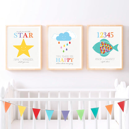 Three nursery prints above a white crib. One smiling star with &quot;Twinkle Twinkle Little Star.&quot; Another a blue cloud with colourful raindrops and &quot;You Make Me Happy.&quot; The third  a multicoloured fish with numbers 1-5 and &quot;Once I Caught a Fish Alive.&quot;