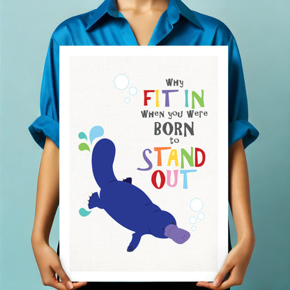 Colourful kids wall art with playful platypus and quote Why fit in when you were born to stand out. Gender neutral nursery art with an Australian animal in a whimsical style. Perfect for kids room decor the printed poster is held by a person in blue.