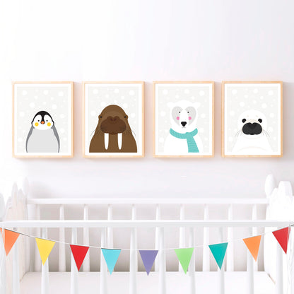 Four prints are displayed above a crib. Each print features a different animal illustration: a penguin, a walrus, a polar bear with a scarf, and a seal. The background of each print is light with subtle snow, creating a cohesive winter theme.