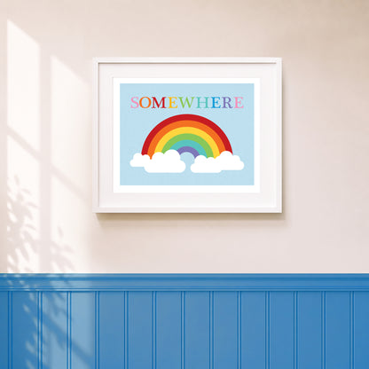 An art print featuring a colorful rainbow and the word 'SOMEWHERE' in colourful letters, displayed on a wall above blue wainscoting.