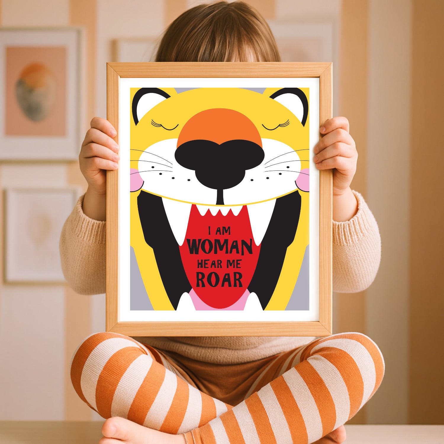 Girl holding a framed illustration of a tiger with text I am woman hear me roar 