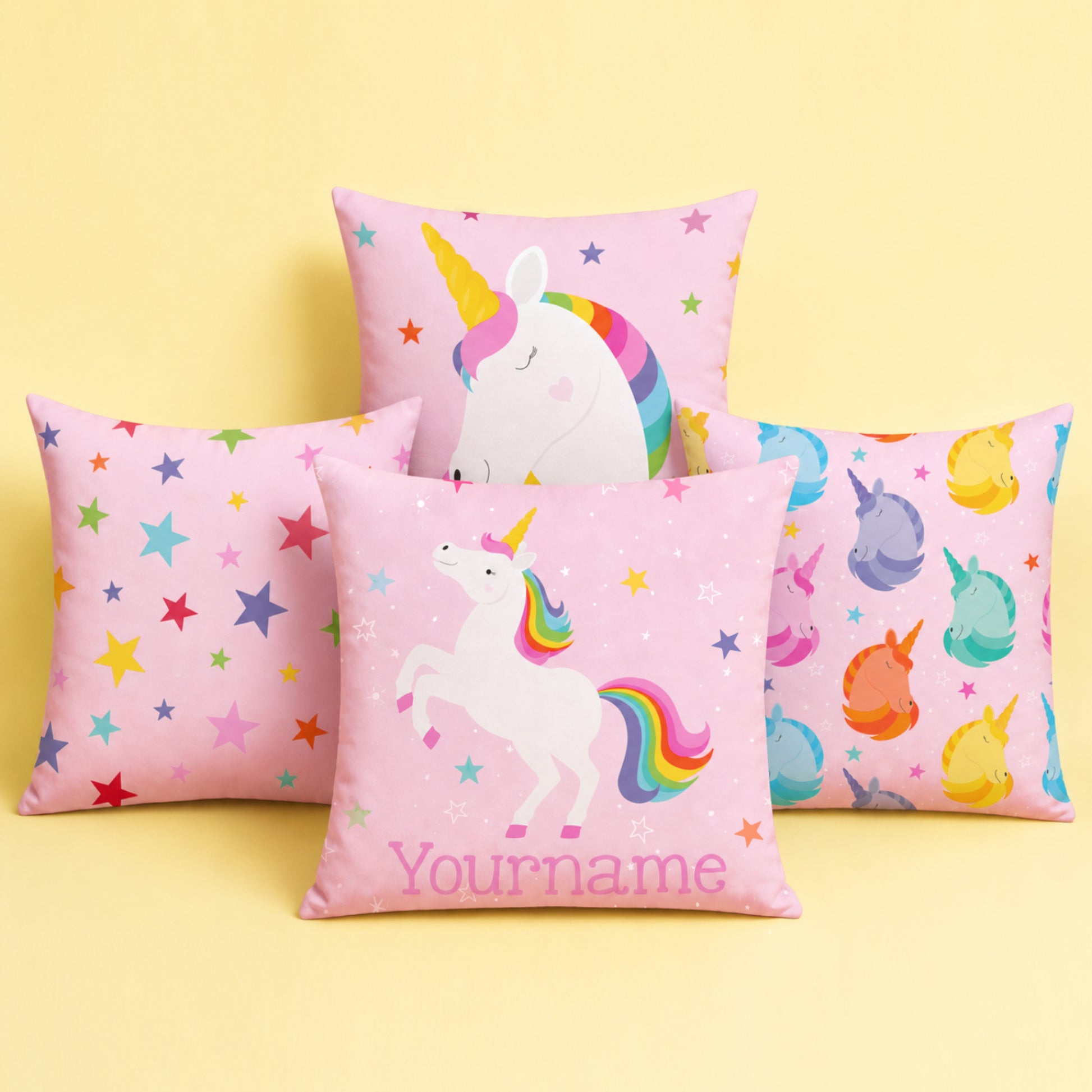 Four pink unicorn-themed pillows with colorful designs on a pink background