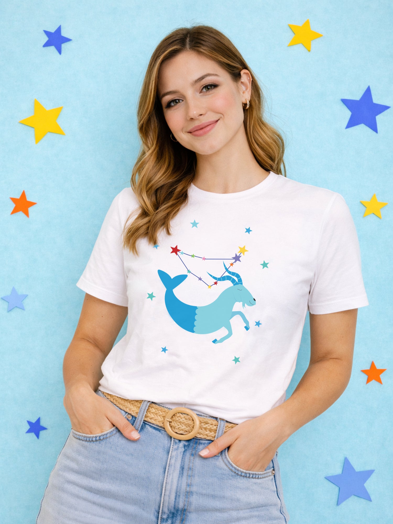 Woman wearing a white t-shirt with a Capricorn graphic design on a blue background with colorful stars.