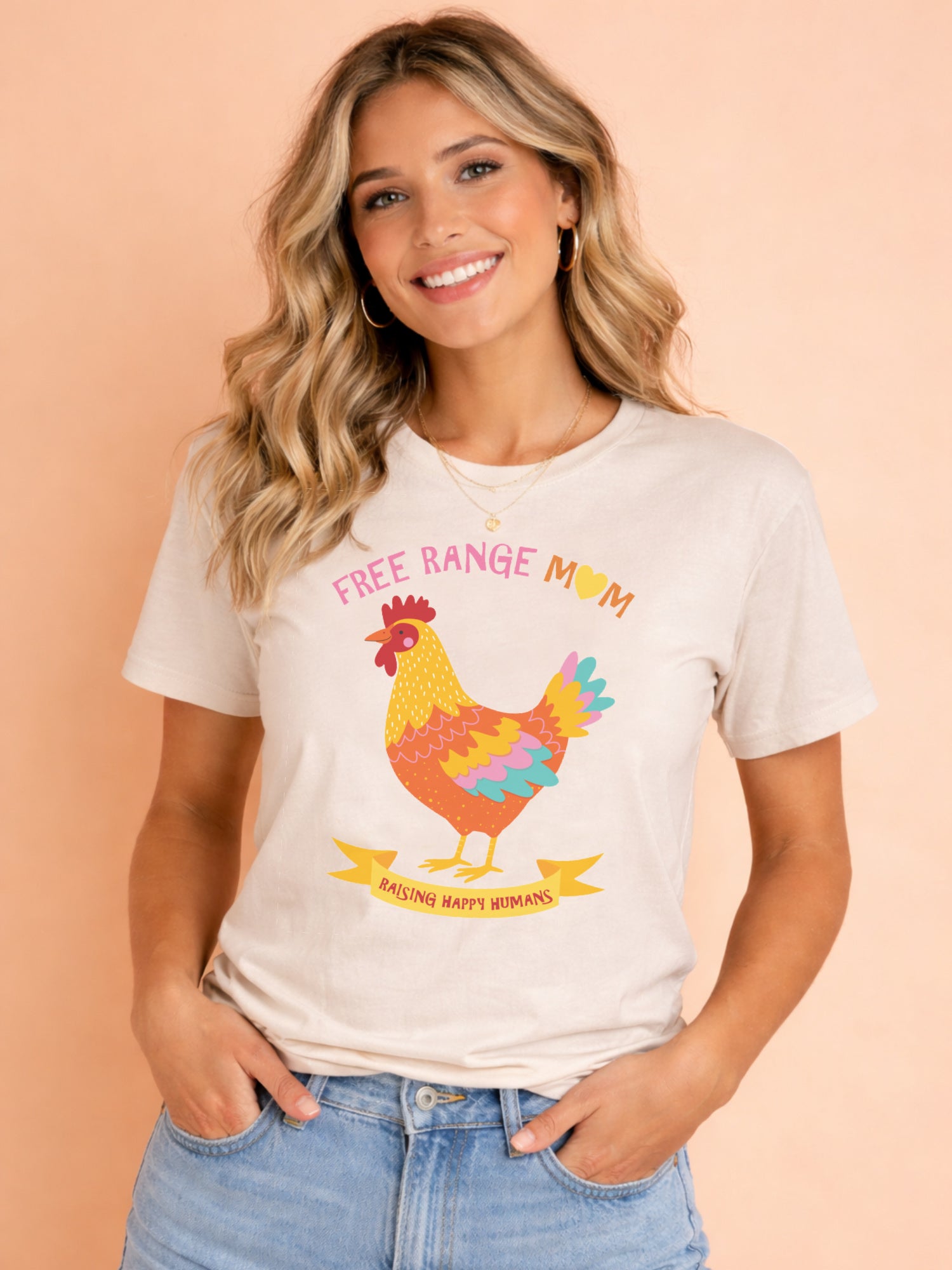 Woman wearing cream Free Range Mum t shirt with colourful chicken design, styled casually with denim shorts against a soft background