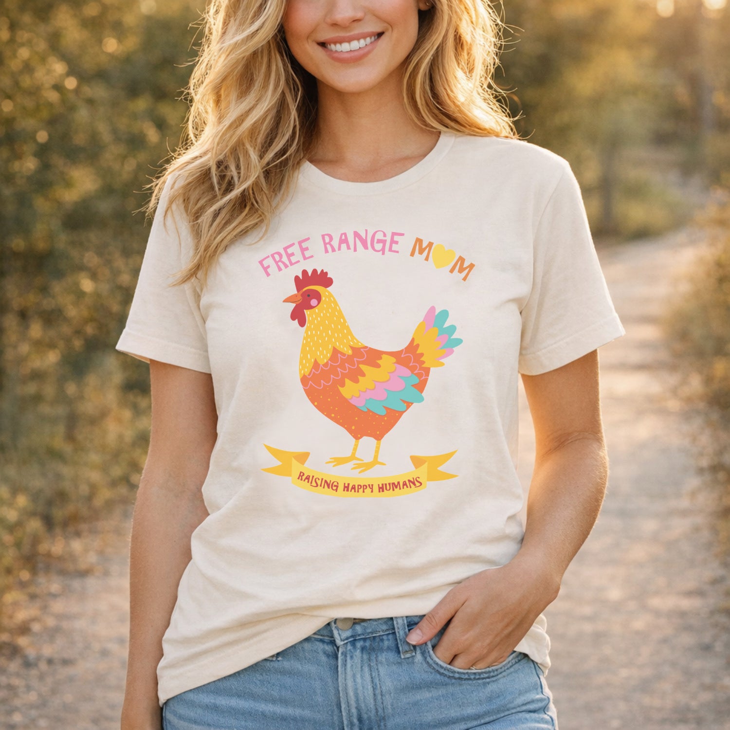 Woman wearing Free Range Mum t shirt outdoors in natural light, styled casually with denim and featuring colourful chicken illustration and motherhood slogan