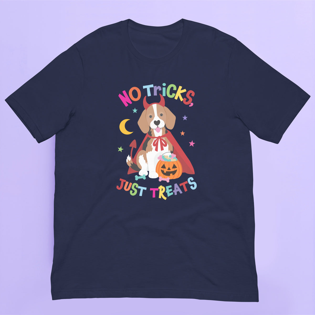 A navy blue short-sleeve Halloween t-shirt with a colorful graphic of a dog dressed as a devil wearing a cape and holding a pumpkin, with the text 'NO TRICKS JUST TREATS' in a playful multicolor font