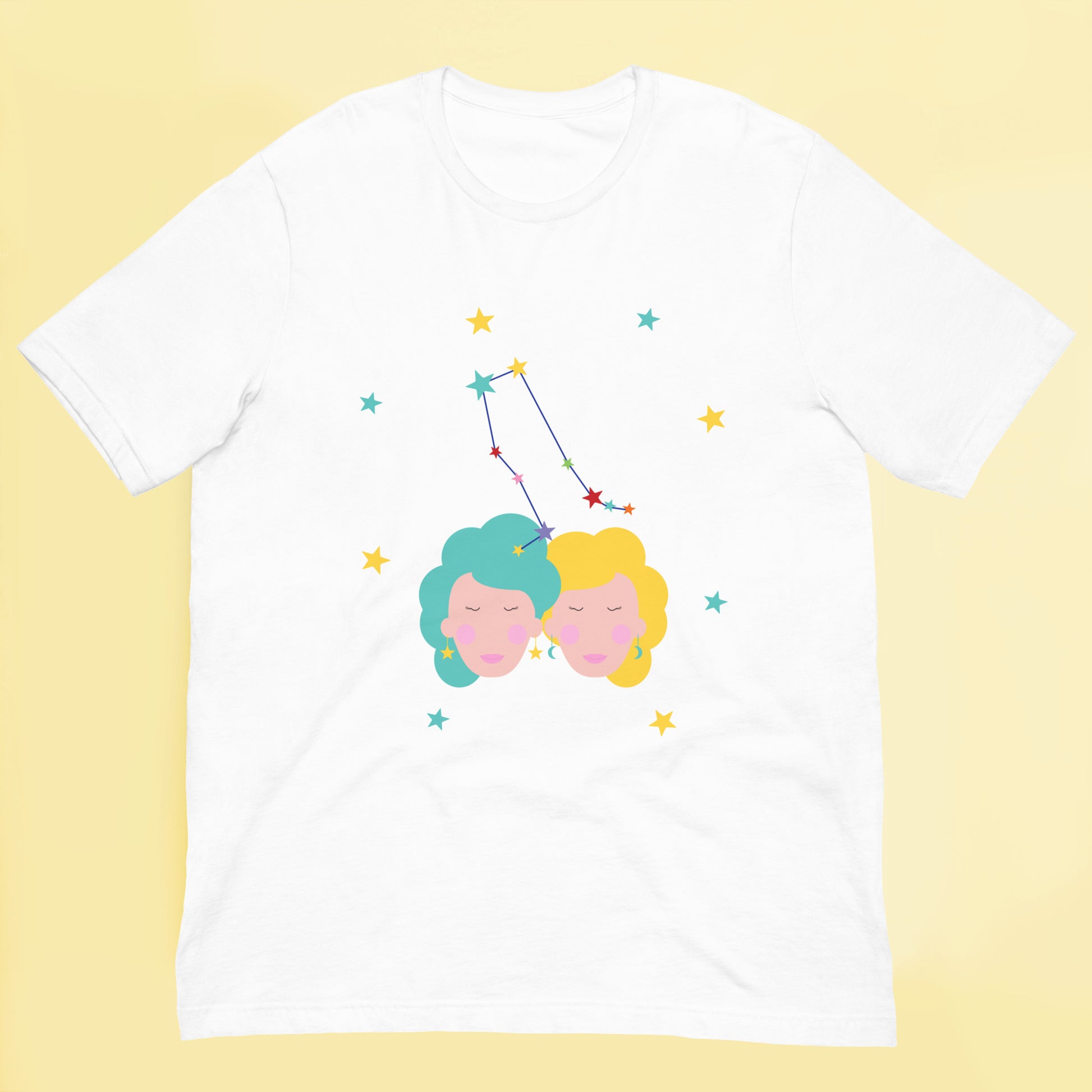 White t-shirt with colorful graphic of gemini two faces and a constellation on a yellow background