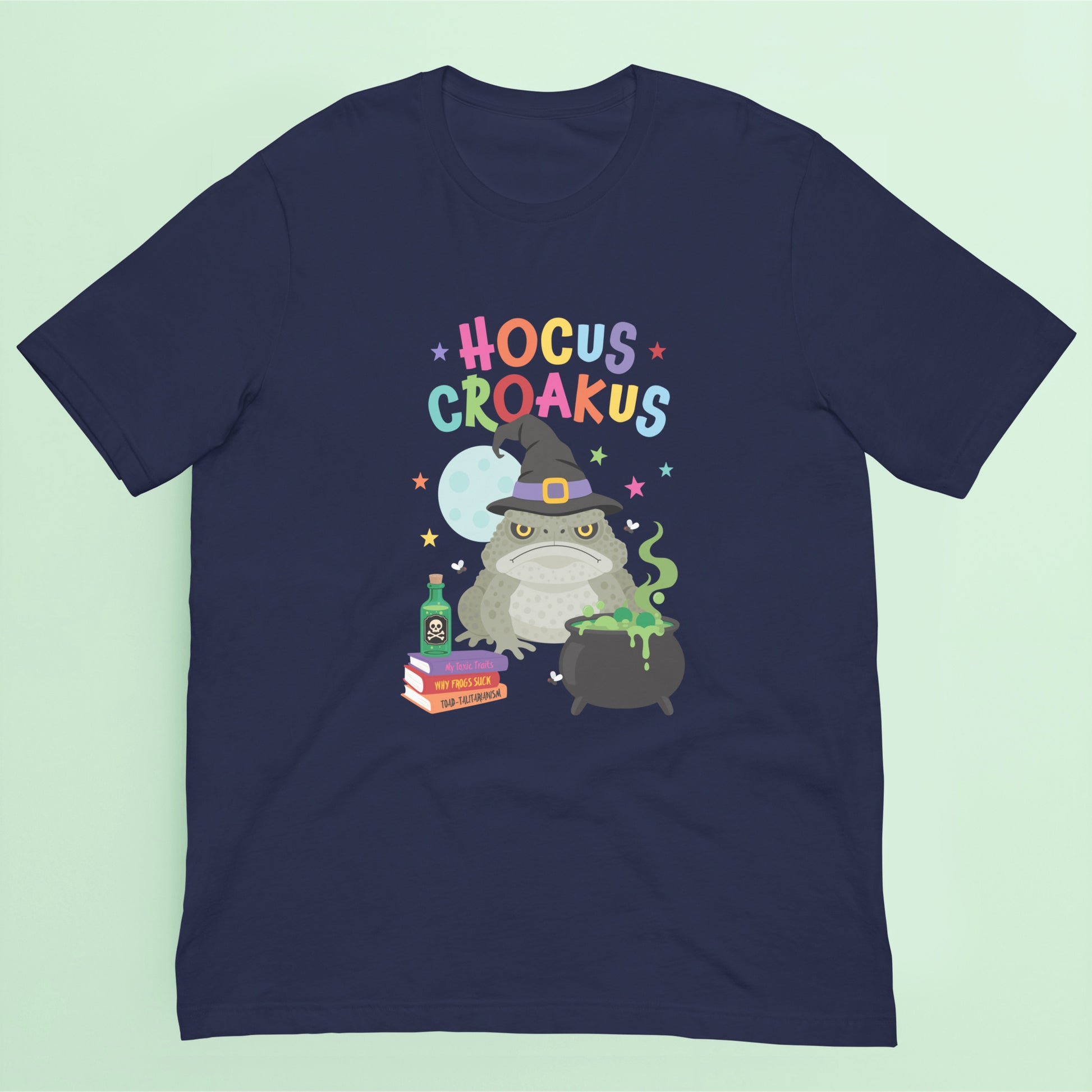 Navy Halloween t shirt featuring a grumpy cane toad dressed as a witch beside a bubbling cauldron with the words "Hocus Croakus".