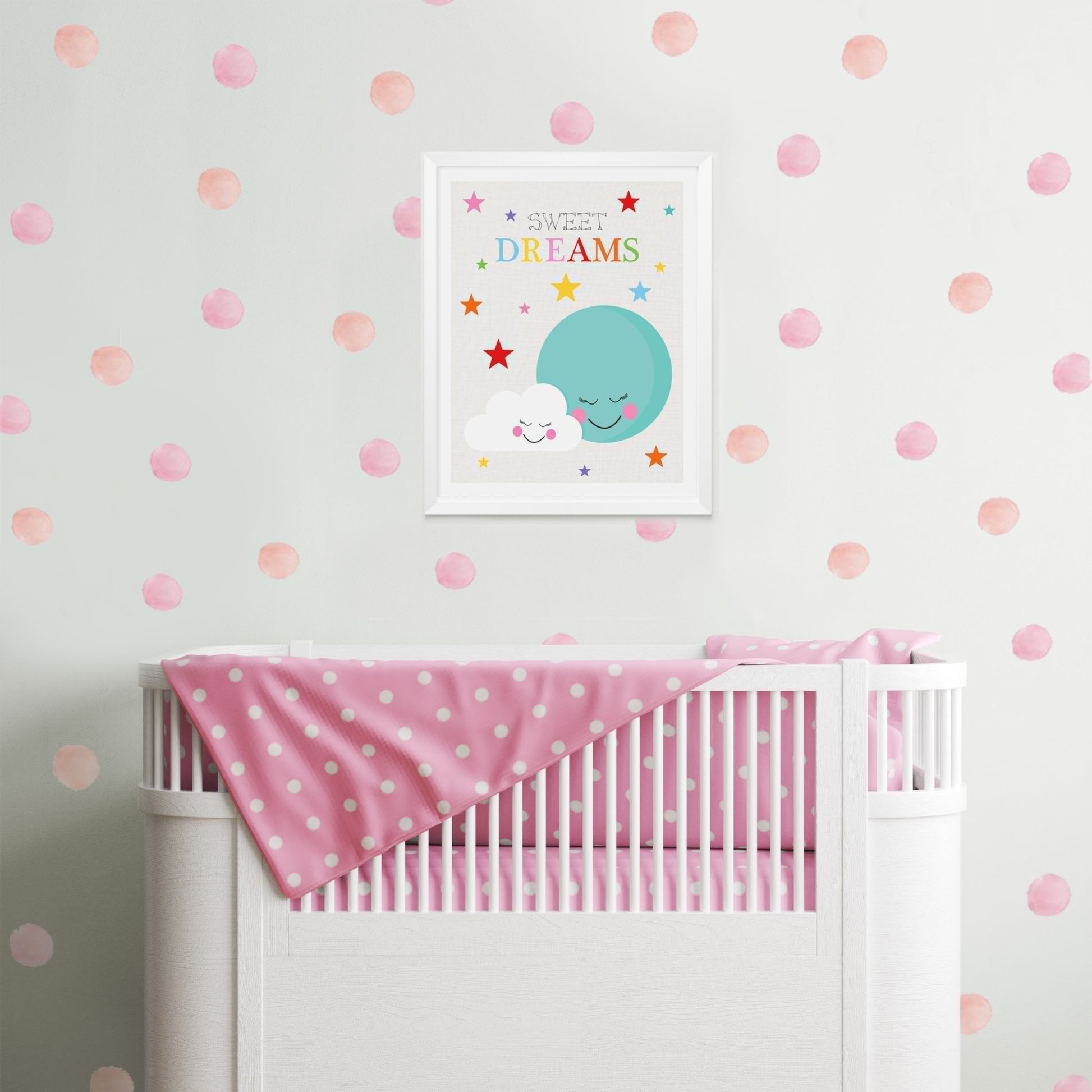 baby girl nursery with pink spots on the wall and cute colourful snuggling moon and cloud print with sweet dreams over cot