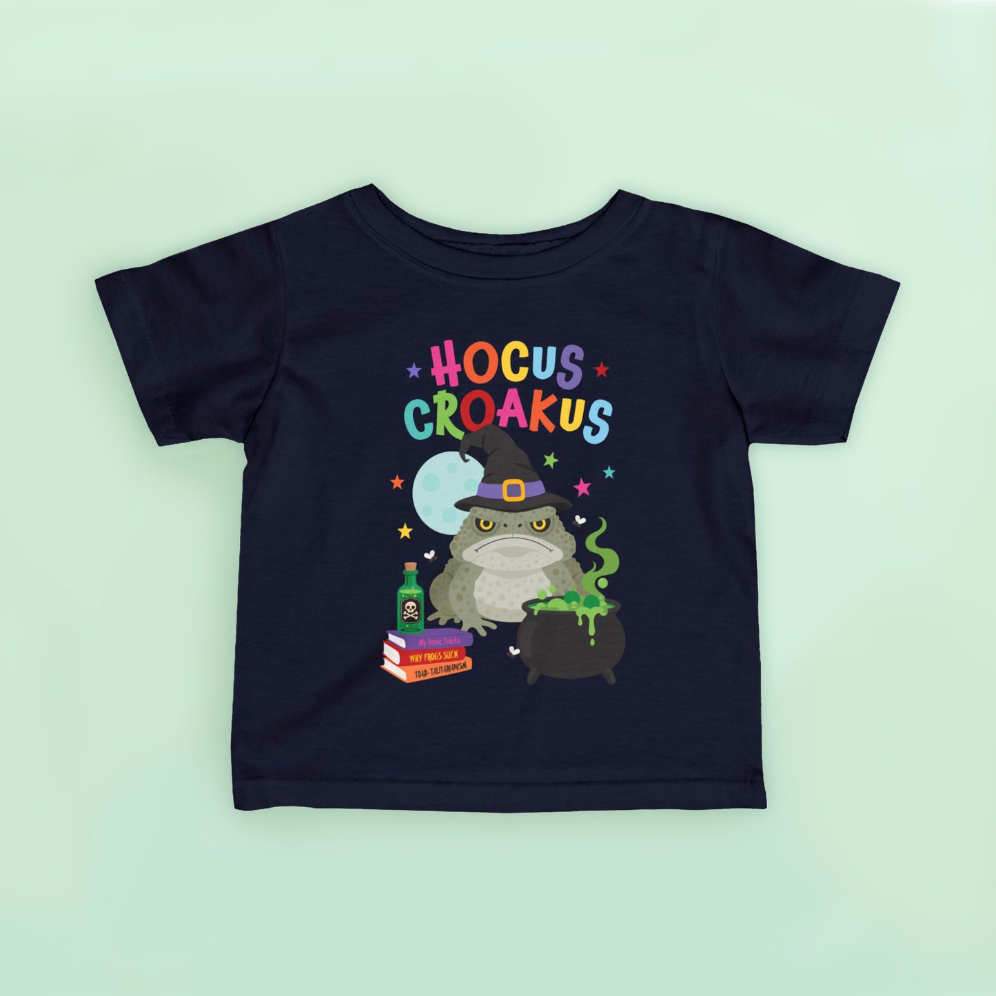 Navy blue kids Halloween t shirt featuring a grumpy cane toad dressed as a witch beside a bubbling cauldron with the words "Hocus Croakus".